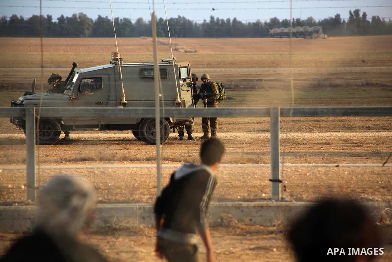 Palestinians stand near the Israeli Gaza border fence in east of Khan Younis, southern Gaza Strip, Friday, Nov. 23, 2012. Hundreds of Gaza crowds surged toward Israel's border fence with the Hamas-ruled territory, in a n...
