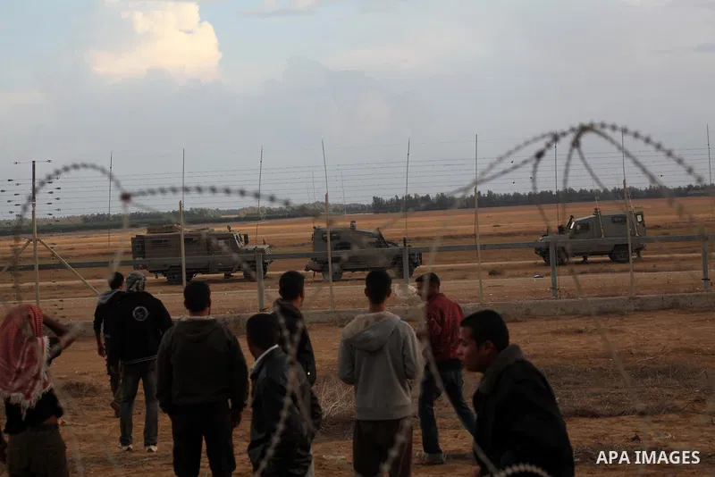 Palestinians stand near the Israeli Gaza border fence in east of Khan Younis, southern Gaza Strip, Friday, Nov. 23, 2012. Hundreds of Gaza crowds surged toward Israel's border fence with the Hamas-ruled territory, in a n...
