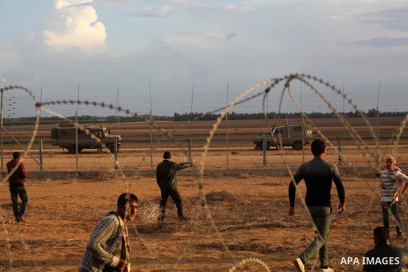 Palestinians stand near the Israeli Gaza border fence in east of Khan Younis, southern Gaza Strip, Friday, Nov. 23, 2012. Hundreds of Gaza crowds surged toward Israel's border fence with the Hamas-ruled territory, in a n...