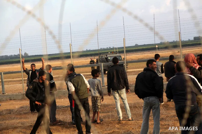 Palestinians stand near the Israeli Gaza border fence in east of Khan Younis, southern Gaza Strip, Friday, Nov. 23, 2012. Hundreds of Gaza crowds surged toward Israel's border fence with the Hamas-ruled territory, in a n...