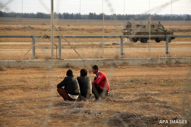 Palestinians stand near the Israeli Gaza border fence in east of Khan Younis, southern Gaza Strip, Friday, Nov. 23, 2012. Hundreds of Gaza crowds surged toward Israel's border fence with the Hamas-ruled territory, in a n...