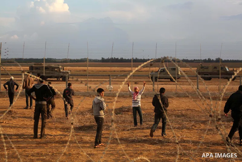 Palestinians stand near the Israeli Gaza border fence in east of Khan Younis, southern Gaza Strip, Friday, Nov. 23, 2012. Hundreds of Gaza crowds surged toward Israel's border fence with the Hamas-ruled territory, in a n...