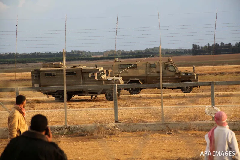 Palestinians stand near the Israeli Gaza border fence in east of Khan Younis, southern Gaza Strip, Friday, Nov. 23, 2012. Hundreds of Gaza crowds surged toward Israel's border fence with the Hamas-ruled territory, in a n...