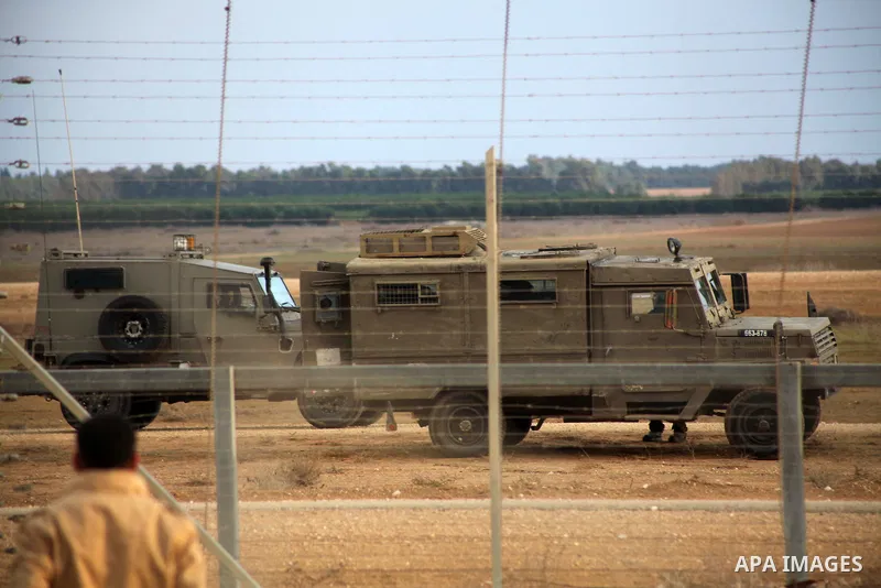 Palestinians stand near the Israeli Gaza border fence in east of Khan Younis, southern Gaza Strip, Friday, Nov. 23, 2012. Hundreds of Gaza crowds surged toward Israel's border fence with the Hamas-ruled territory, in a n...