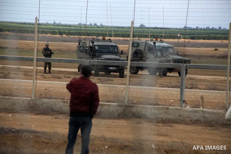 Palestinians stand near the Israeli Gaza border fence in east of Khan Younis, southern Gaza Strip, Friday, Nov. 23, 2012. Hundreds of Gaza crowds surged toward Israel's border fence with the Hamas-ruled territory, in a n...