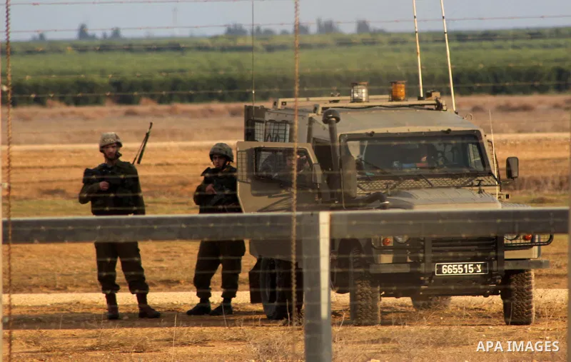 Israeli troops stand guard near the Israeli Gaza border fence in east of Khan Younis, southern Gaza Strip, Friday, Nov. 23, 2012. Hundreds of Gaza crowds surged toward Israel's border fence with the Hamas-ruled territory...
