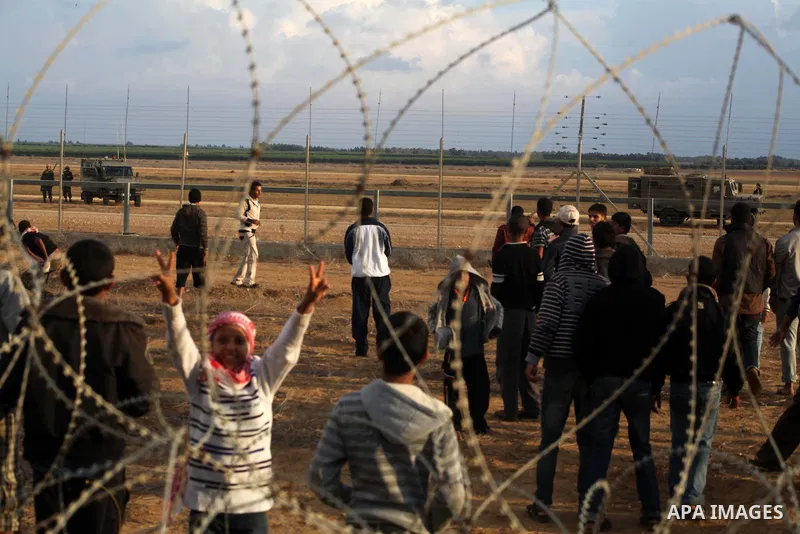 Palestinians stand near the Israeli Gaza border fence in east of Khan Younis, southern Gaza Strip, Friday, Nov. 23, 2012. Hundreds of Gaza crowds surged toward Israel's border fence with the Hamas-ruled territory, in a n...
