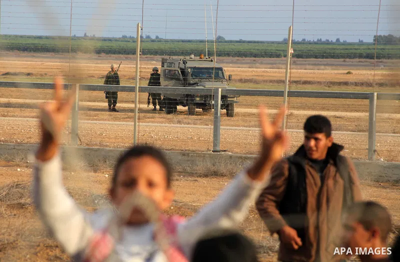 Palestinians stand near the Israeli Gaza border fence in east of Khan Younis, southern Gaza Strip, Friday, Nov. 23, 2012. Hundreds of Gaza crowds surged toward Israel's border fence with the Hamas-ruled territory, in a n...