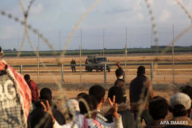 Palestinians stand near the Israeli Gaza border fence in east of Khan Younis, southern Gaza Strip, Friday, Nov. 23, 2012. Hundreds of Gaza crowds surged toward Israel's border fence with the Hamas-ruled territory, in a n...
