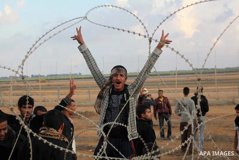 Palestinians stand near the Israeli Gaza border fence in east of Khan Younis, southern Gaza Strip, Friday, Nov. 23, 2012. Hundreds of Gaza crowds surged toward Israel's border fence with the Hamas-ruled territory, in a n...