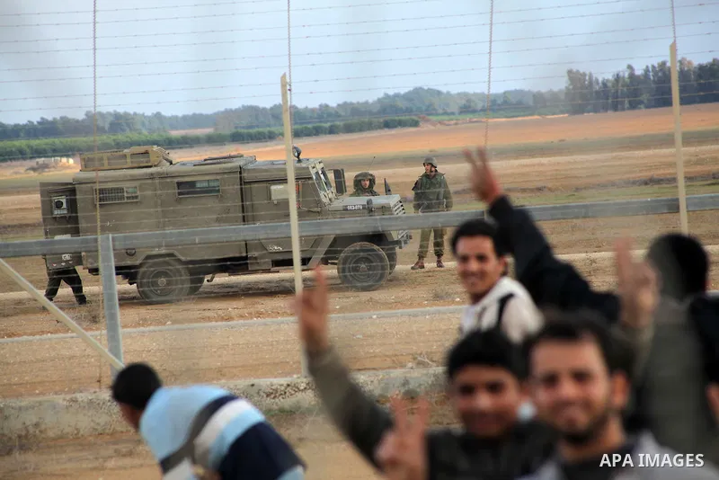 Palestinians stand near the Israeli Gaza border fence in east of Khan Younis, southern Gaza Strip, Friday, Nov. 23, 2012. Hundreds of Gaza crowds surged toward Israel's border fence with the Hamas-ruled territory, in a n...
