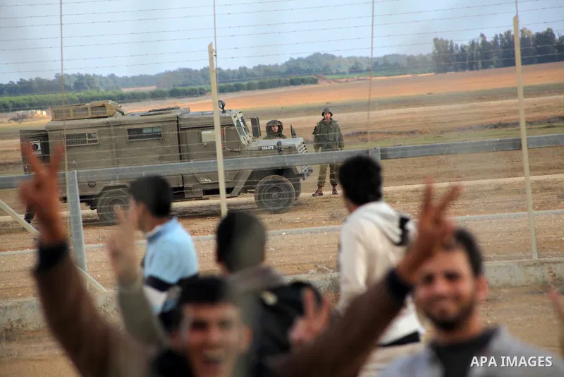 Palestinians stand near the Israeli Gaza border fence in east of Khan Younis, southern Gaza Strip, Friday, Nov. 23, 2012. Hundreds of Gaza crowds surged toward Israel's border fence with the Hamas-ruled territory, in a n...