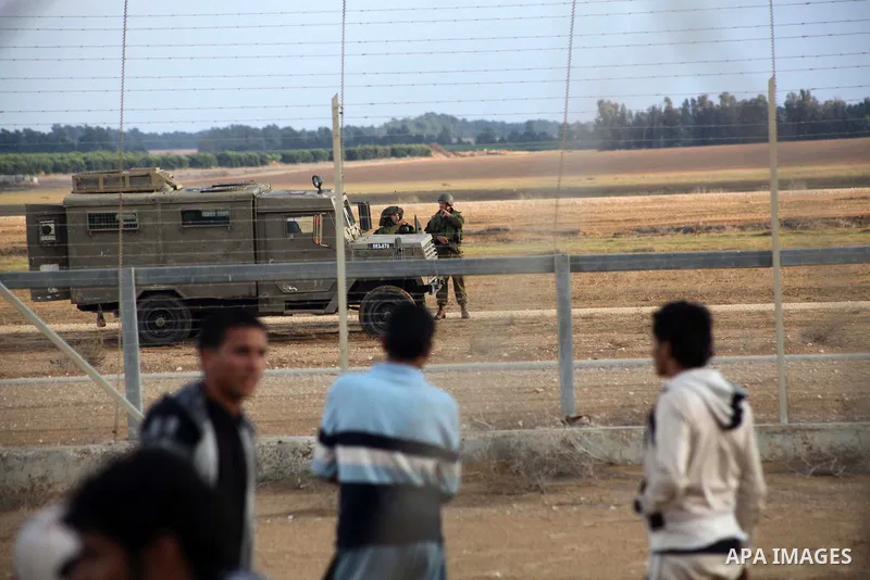 Palestinians stand near the Israeli Gaza border fence in east of Khan Younis, southern Gaza Strip, Friday, Nov. 23, 2012. Hundreds of Gaza crowds surged toward Israel's border fence with the Hamas-ruled territory, in a n...