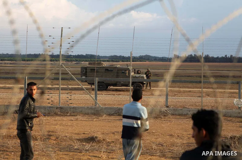 Palestinians stand near the Israeli Gaza border fence in east of Khan Younis, southern Gaza Strip, Friday, Nov. 23, 2012. Hundreds of Gaza crowds surged toward Israel's border fence with the Hamas-ruled territory, in a n...
