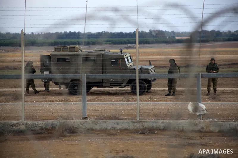 Israeli troops stand guard near the Israeli Gaza border fence in east of Khan Younis, southern Gaza Strip, Friday, Nov. 23, 2012. Hundreds of Gaza crowds surged toward Israel's border fence with the Hamas-ruled territory...