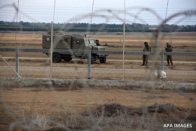 Israeli troops stand guard near the Israeli Gaza border fence in east of Khan Younis, southern Gaza Strip, Friday, Nov. 23, 2012. Hundreds of Gaza crowds surged toward Israel's border fence with the Hamas-ruled territory...