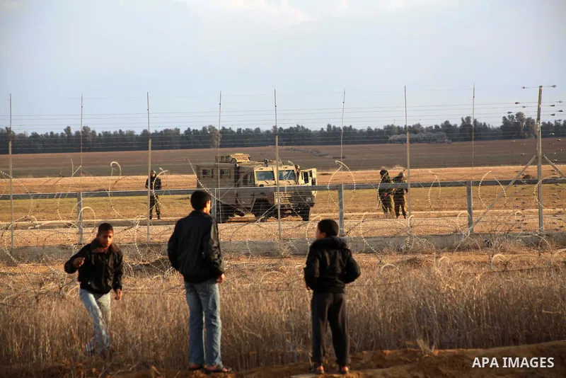 Palestinians stand near the Israeli Gaza border fence in east of Khan Younis, southern Gaza Strip, Friday, Nov. 23, 2012. Hundreds of Gaza crowds surged toward Israel's border fence with the Hamas-ruled territory, in a n...