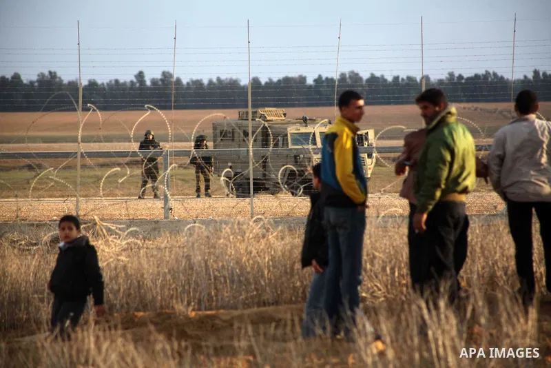 Palestinians stand near the Israeli Gaza border fence in east of Khan Younis, southern Gaza Strip, Friday, Nov. 23, 2012. Hundreds of Gaza crowds surged toward Israel's border fence with the Hamas-ruled territory, in a n...