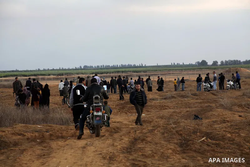 Palestinians stand near the Israeli Gaza border fence in east of Khan Younis, southern Gaza Strip, Friday, Nov. 23, 2012. Hundreds of Gaza crowds surged toward Israel's border fence with the Hamas-ruled territory, in a n...