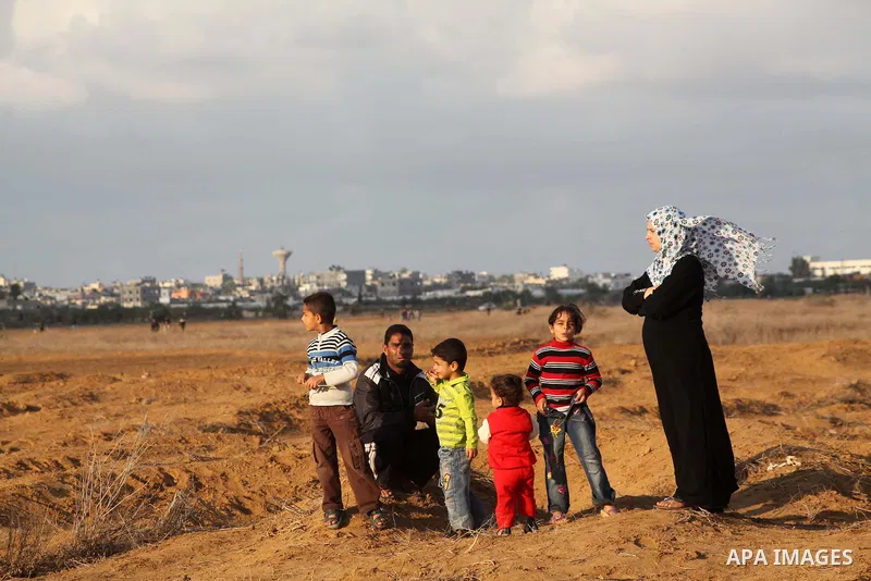 Palestinians stand near the Israeli Gaza border fence in east of Khan Younis, southern Gaza Strip, Friday, Nov. 23, 2012. Hundreds of Gaza crowds surged toward Israel's border fence with the Hamas-ruled territory, in a n...