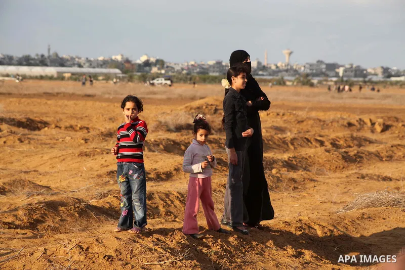 Palestinians stand near the Israeli Gaza border fence in east of Khan Younis, southern Gaza Strip, Friday, Nov. 23, 2012. Hundreds of Gaza crowds surged toward Israel's border fence with the Hamas-ruled territory, in a n...