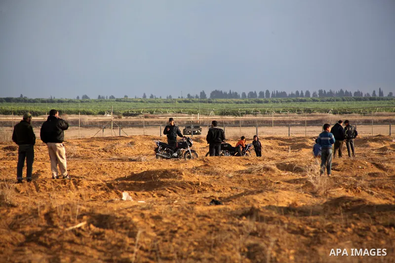 Palestinians stand near the Israeli Gaza border fence in east of Khan Younis, southern Gaza Strip, Friday, Nov. 23, 2012. Hundreds of Gaza crowds surged toward Israel's border fence with the Hamas-ruled territory, in a n...