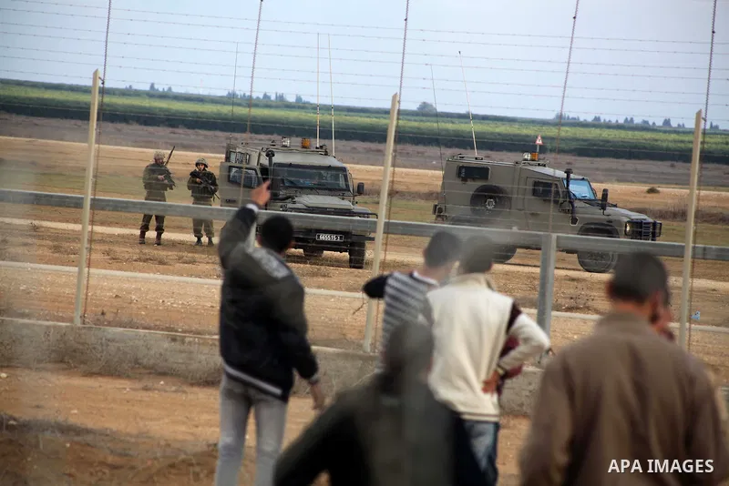 Palestinians stand near the Israeli Gaza border fence in east of Khan Younis, southern Gaza Strip, Friday, Nov. 23, 2012. Hundreds of Gaza crowds surged toward Israel's border fence with the Hamas-ruled territory, in a n...