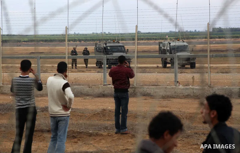 Palestinians stand near the Israeli Gaza border fence in east of Khan Younis, southern Gaza Strip, Friday, Nov. 23, 2012. Hundreds of Gaza crowds surged toward Israel's border fence with the Hamas-ruled territory, in a n...
