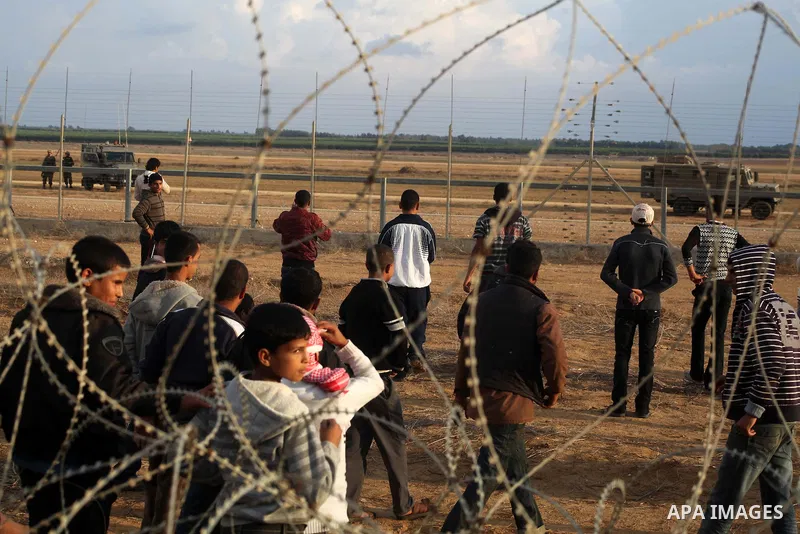 Palestinians stand near the Israeli Gaza border fence in east of Khan Younis, southern Gaza Strip, Friday, Nov. 23, 2012. Hundreds of Gaza crowds surged toward Israel's border fence with the Hamas-ruled territory, in a n...