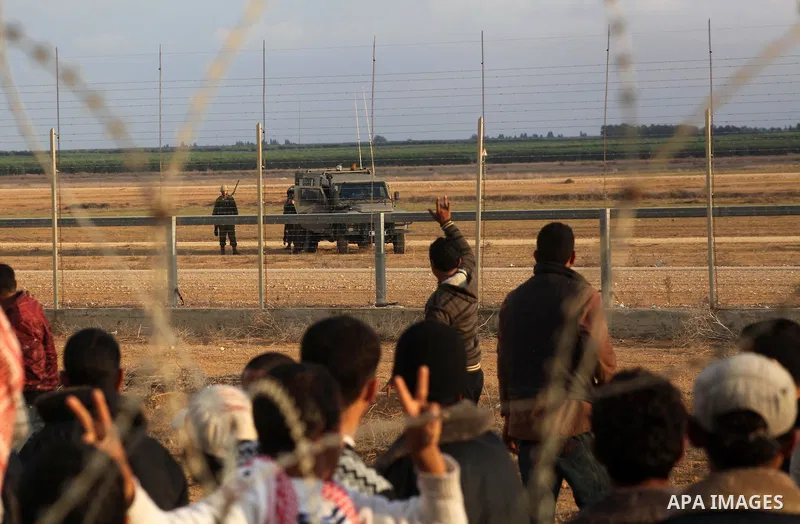 Palestinians stand near the Israeli Gaza border fence in east of Khan Younis, southern Gaza Strip, Friday, Nov. 23, 2012. Hundreds of Gaza crowds surged toward Israel's border fence with the Hamas-ruled territory, in a n...