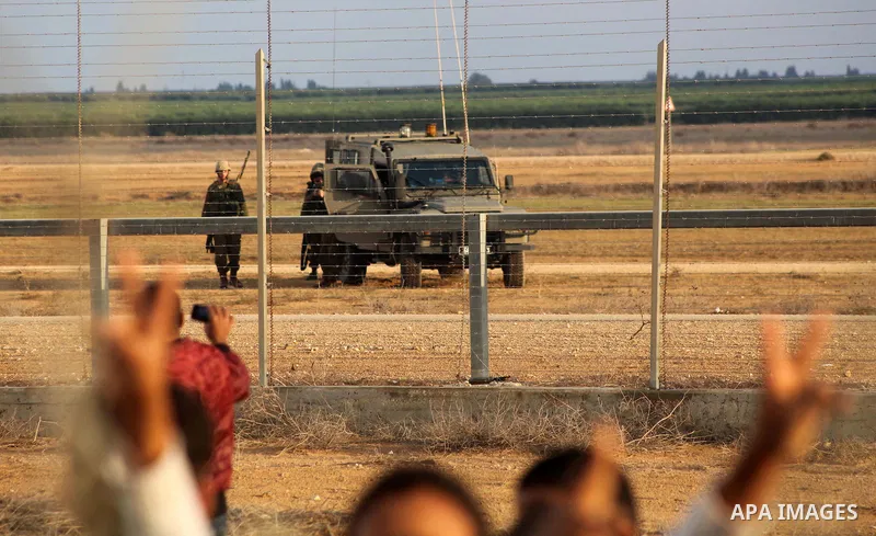 Palestinians stand near the Israeli Gaza border fence in east of Khan Younis, southern Gaza Strip, Friday, Nov. 23, 2012. Hundreds of Gaza crowds surged toward Israel's border fence with the Hamas-ruled territory, in a n...