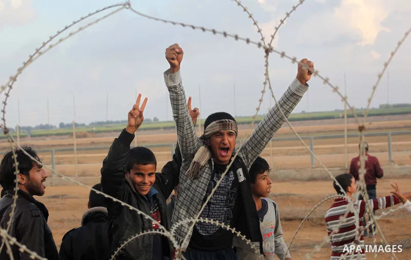 Palestinians stand near the Israeli Gaza border fence in east of Khan Younis, southern Gaza Strip, Friday, Nov. 23, 2012. Hundreds of Gaza crowds surged toward Israel's border fence with the Hamas-ruled territory, in a n...