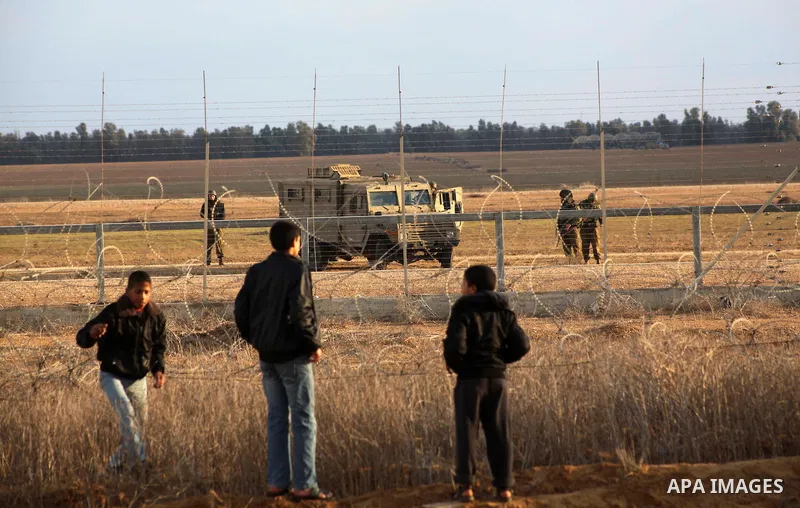 Palestinians stand near the Israeli Gaza border fence in east of Khan Younis, southern Gaza Strip, Friday, Nov. 23, 2012. Hundreds of Gaza crowds surged toward Israel's border fence with the Hamas-ruled territory, in a n...