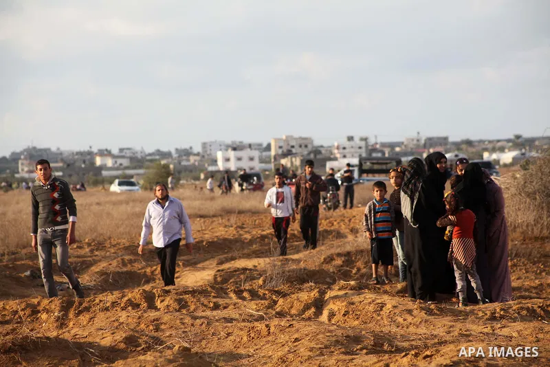 Palestinians stand near the Israeli Gaza border fence in east of Khan Younis, southern Gaza Strip, Friday, Nov. 23, 2012. Hundreds of Gaza crowds surged toward Israel's border fence with the Hamas-ruled territory, in a n...