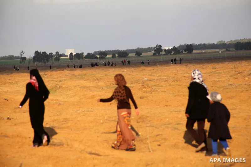 Palestinians stand near the Israeli Gaza border fence in east of Khan Younis, southern Gaza Strip, Friday, Nov. 23, 2012. Hundreds of Gaza crowds surged toward Israel's border fence with the Hamas-ruled territory, in a n...