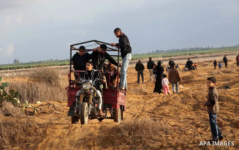 Palestinians ride there tricycles near the Israeli Gaza border fence in east of Khan Younis, southern Gaza Strip, Friday, Nov. 23, 2012. Hundreds of Gaza crowds surged toward Israel's border fence with the Hamas-ruled te...