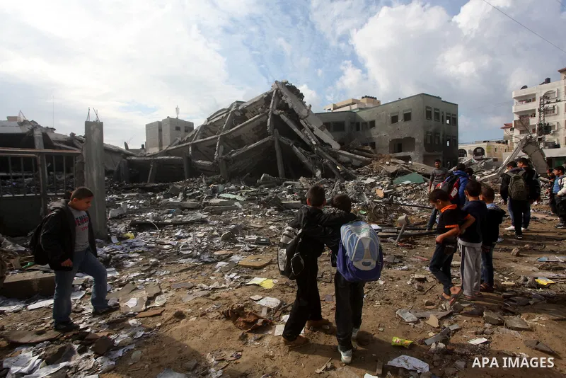 Palestinians school buys walk on the rubble of a building destroyed during earlier Israeli bombardment, as they make their way to their nearby school in Gaza City, on November 24, 2012, three days after a truce was decla...