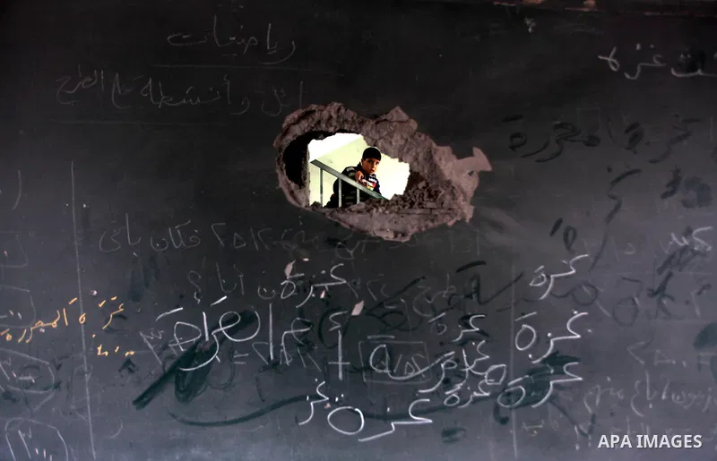 A Palestinian school boy looks through a hole at their damaged United Nations run school in Gaza City, on November 24, 2012, three days after a truce was declared between Israel and Hamas. Gaza's children, virtually abse...