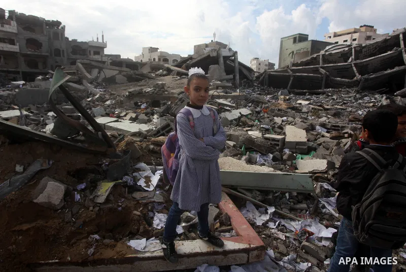 Palestinians school girls walk on the rubble of a building destroyed during earlier Israeli bombardment, as they make their way to their nearby school in Gaza City, on November 24, 2012, three days after a truce was decl...