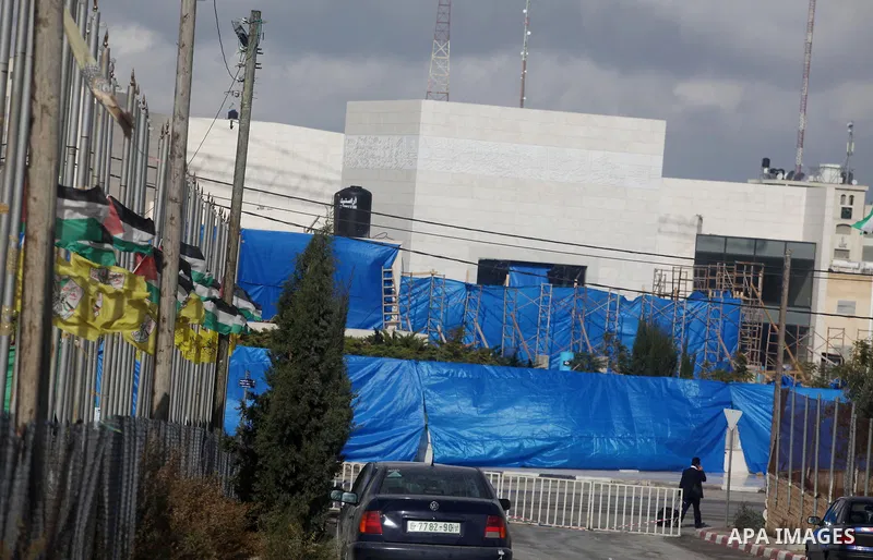 A Palestinian security officer stands in front of plastic tarpaulin erected around the mausoleum of the late Palestinian leader Yasser Arafat, in the West Bank city of Ramallah, on November 24, 2012. The body of Arafat w...