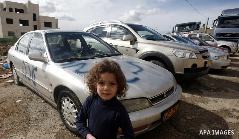 A Palestinian girl stands next to a car with a graffiti reading in Hebrew "Gaza: the price to pay" in the Palestinian neighborhood of Shuafat in Israeli annexed East Jerusalem, , on November 25, 2012. Unknown assailants...
