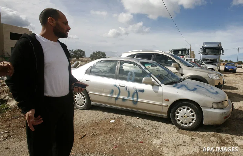 A Palestinian man stands next to a car with a graffiti reading in Hebrew "Gaza: the price to pay" in the Palestinian neighborhood of Shuafat in Israeli annexed East Jerusalem, , on November 25, 2012. Unknown assailants v...