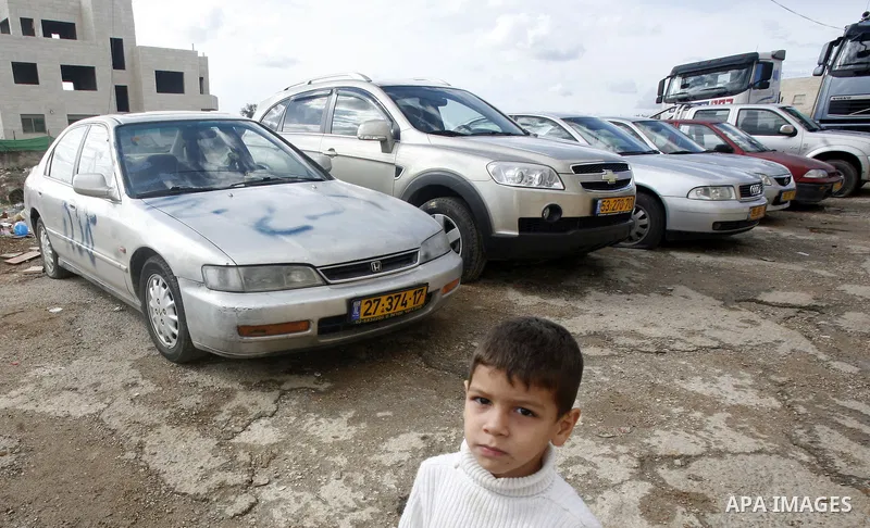 A Palestinian boy stands next to a car with a graffiti reading in Hebrew "Gaza: the price to pay" in the Palestinian neighborhood of Shuafat in Israeli annexed East Jerusalem, , on November 25, 2012. Unknown assailants v...
