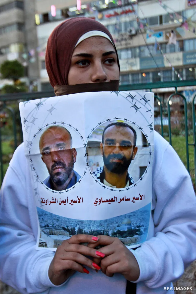 A Palestinian woman holds a poster of Palestinian prisoners during a protest calling for the release them from Israeli jails and in support of prisoners on hunger strike, in the West Bank city of Nablus on 26 November 20...