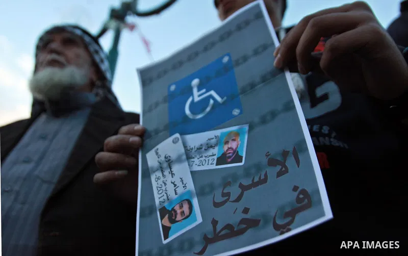Palestinians hold a poster of Palestinian prisoners during a protest calling for the release them from Israeli jails and in support of prisoners on hunger strike, in the West Bank city of Nablus on 26 November 2012. Phot...