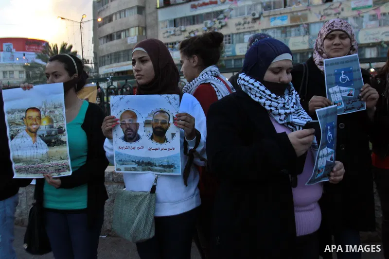 Palestinians hold a poster of Palestinian prisoners during a protest calling for the release them from Israeli jails and in support of prisoners on hunger strike, in the West Bank city of Nablus on 26 November 2012. Phot...