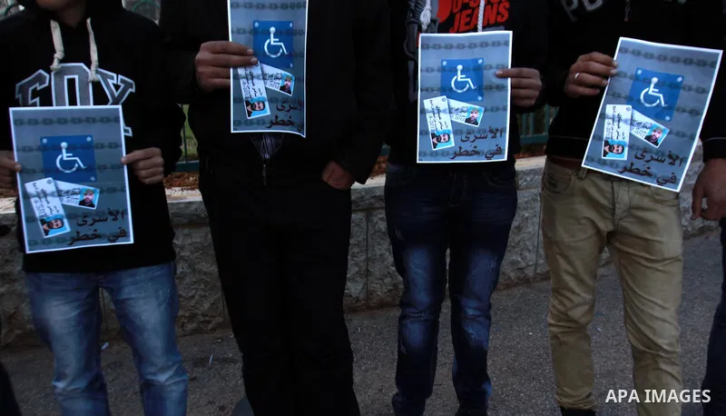 Palestinians hold a poster of Palestinian prisoners during a protest calling for the release them from Israeli jails and in support of prisoners on hunger strike, in the West Bank city of Nablus on 26 November 2012. Phot...