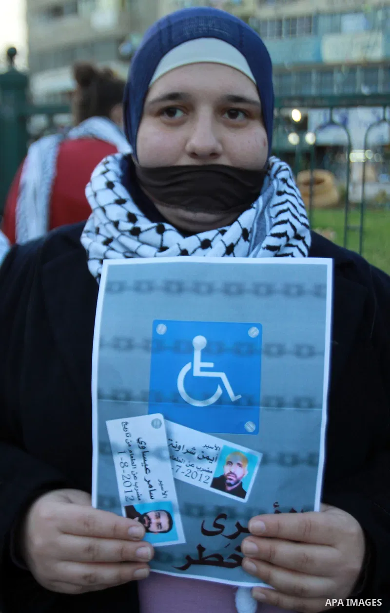 A Palestinian woman holds a poster of Palestinian prisoners during a protest calling for the release them from Israeli jails and in support of prisoners on hunger strike, in the West Bank city of Nablus on 26 November 20...