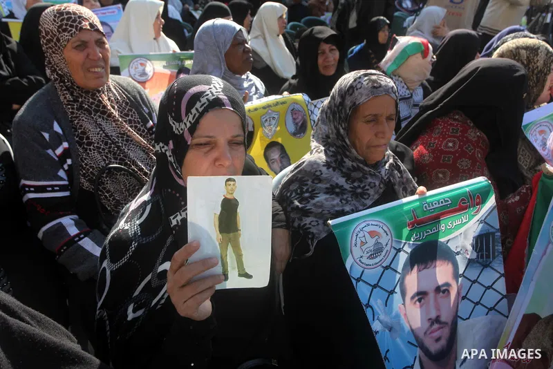 Palestinian women hold a poster of Palestinian prisoners during a protest calling for the release them from Israeli jails and in support of prisoners on hunger strike in front of Red Cross, in Gaza city on 26 November 20...