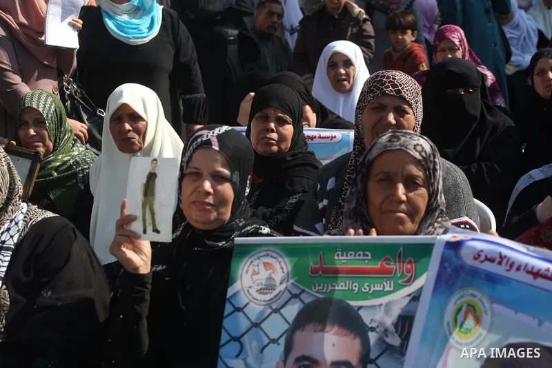 Palestinian women hold a poster of Palestinian prisoners during a protest calling for the release them from Israeli jails and in support of prisoners on hunger strike in front of Red Cross, in Gaza city on 26 November 20...